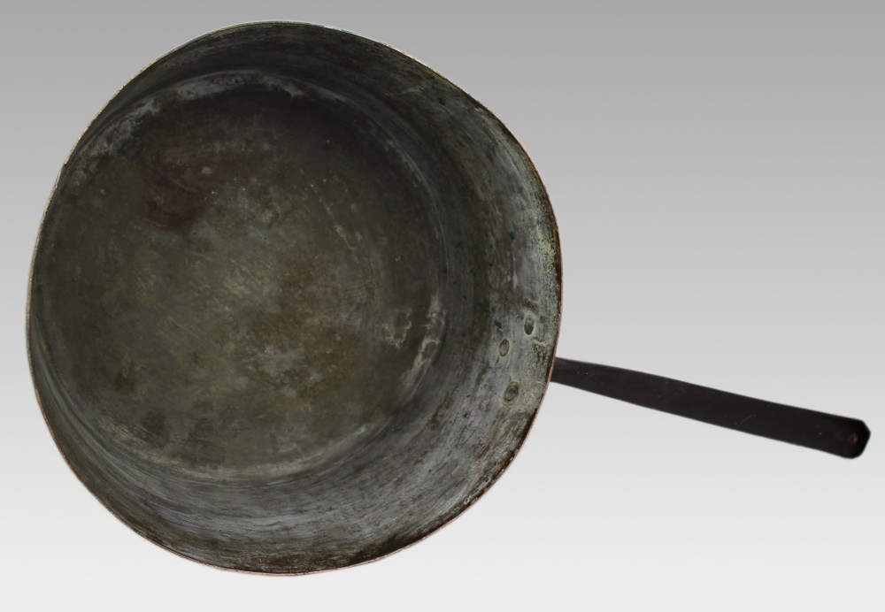 A large antique Georgian copper saucepan featuring a straight cylindrical body and a long wrought iron handle fastened with metal rivets. View X