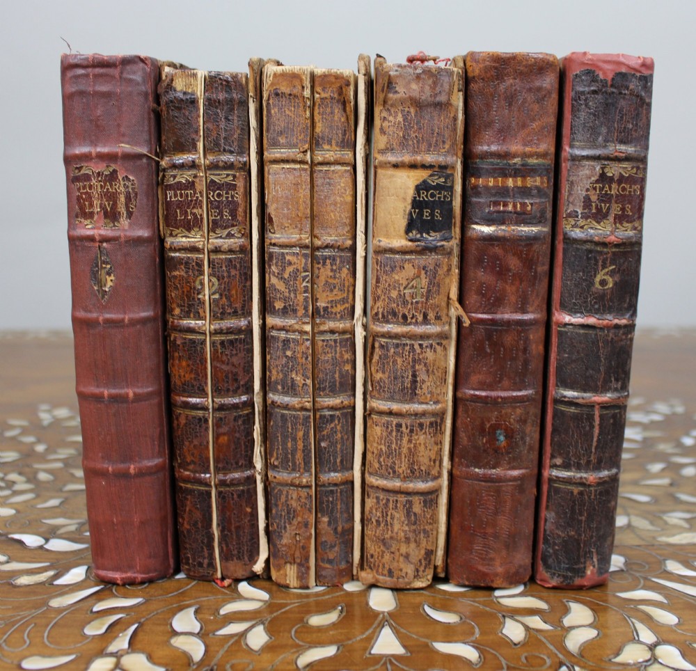 A six-volume set of eighteenth-century leather-bound books with distressed brown spines and gilt lettering standing upright.