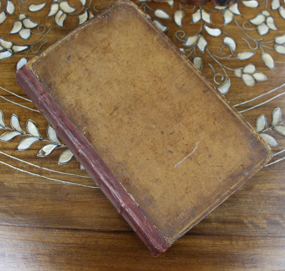 A six-volume set of eighteenth-century leather-bound books with distressed brown spines and gilt lettering standing upright. View VII