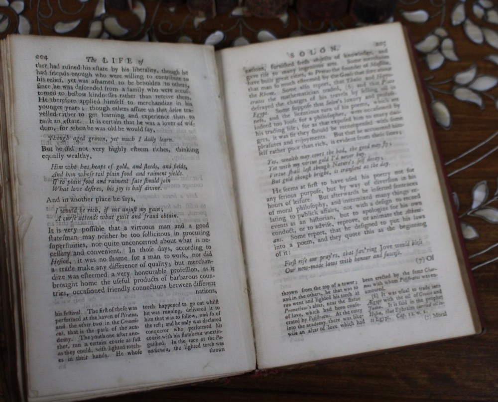 A six-volume set of eighteenth-century leather-bound books with distressed brown spines and gilt lettering standing upright. View XI
