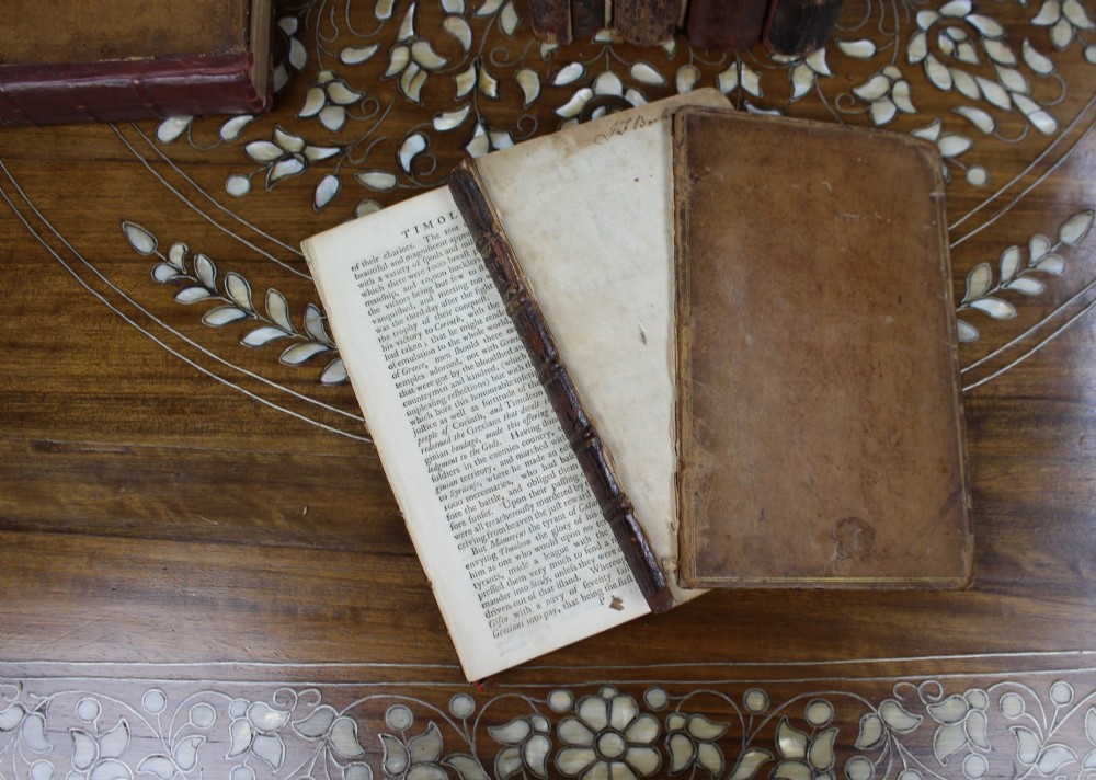 A six-volume set of eighteenth-century leather-bound books with distressed brown spines and gilt lettering standing upright. View XII
