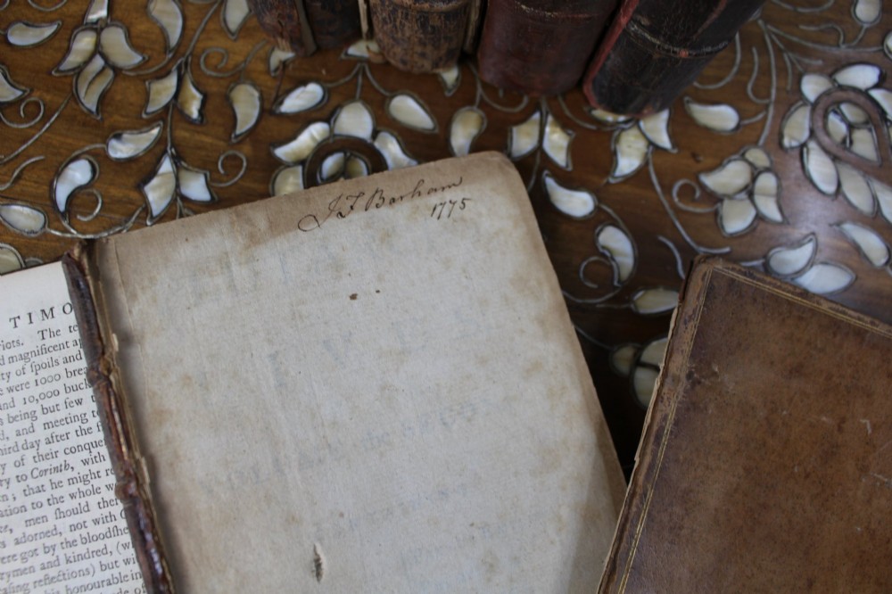 A six-volume set of eighteenth-century leather-bound books with distressed brown spines and gilt lettering standing upright. View XIII