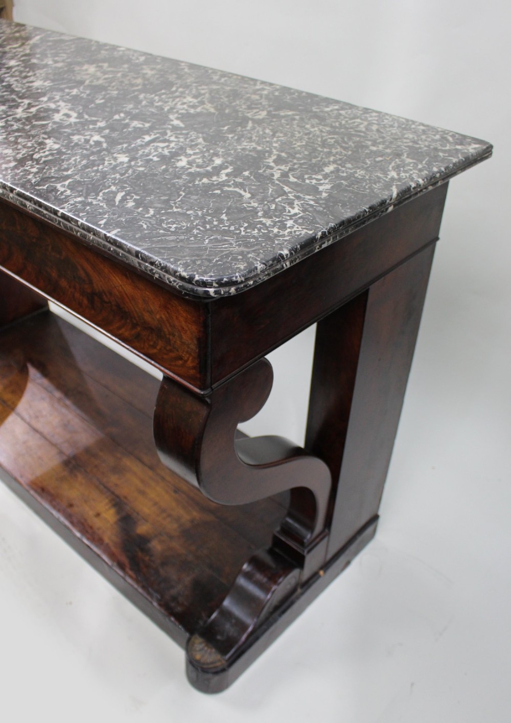 An antique dark mahogany French console table featuring a grey and white mottled marble top, curved scroll legs, and a low plinth shelf. View VIII