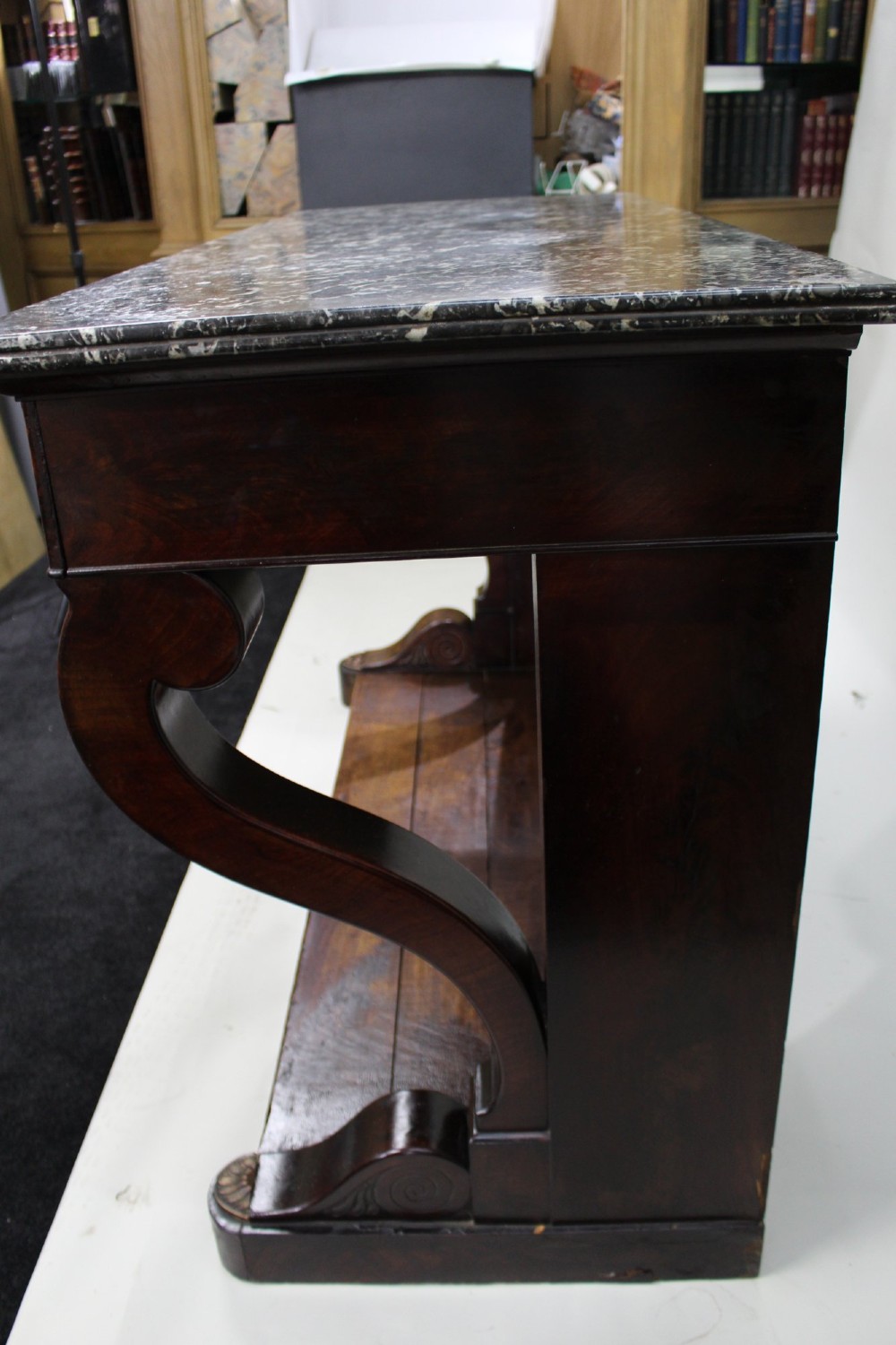 An antique dark mahogany French console table featuring a grey and white mottled marble top, curved scroll legs, and a low plinth shelf. View XI