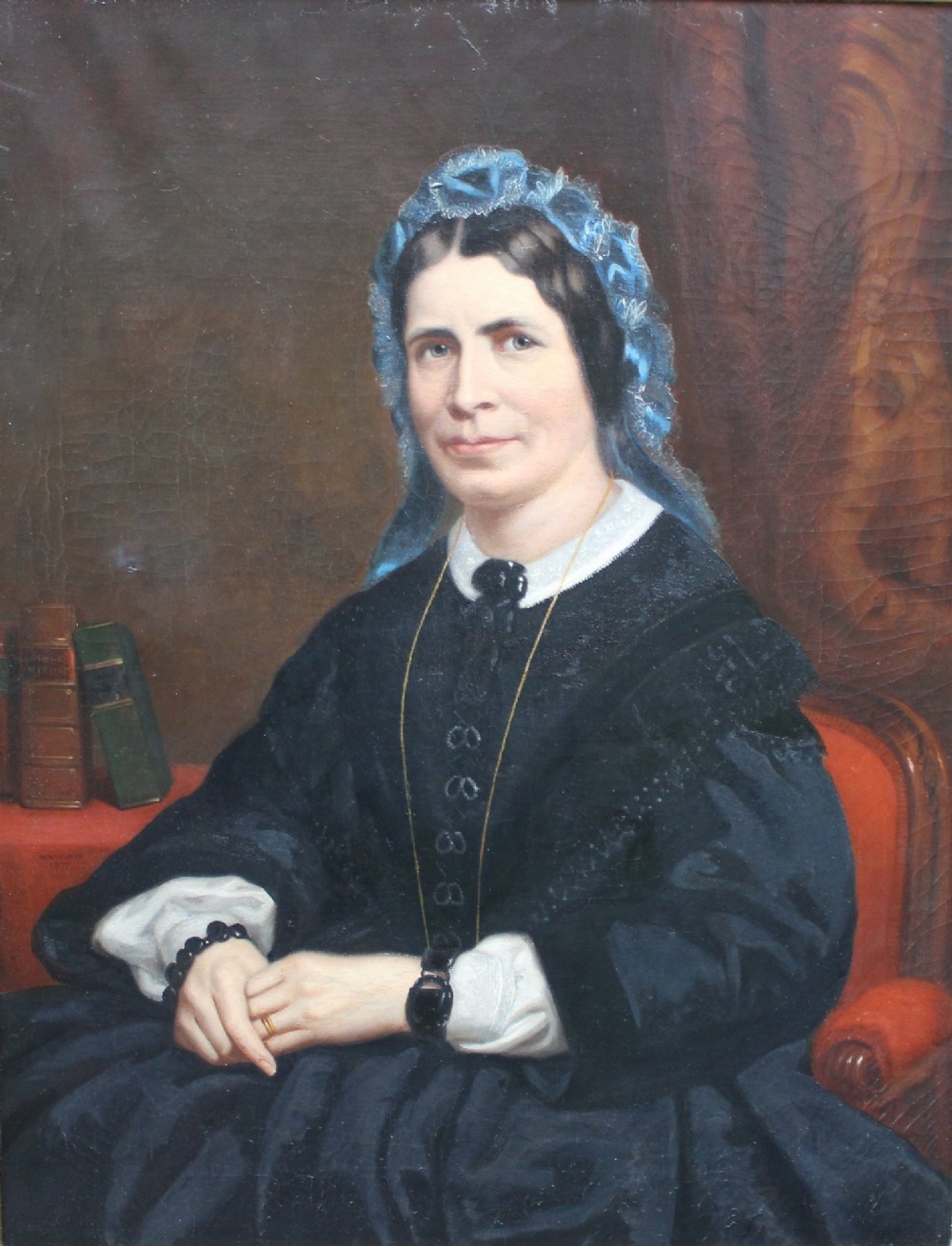 A 19th-century oil painting depicting a seated woman in a dark gown and blue lace bonnet, set within an ornate gold gilt frame. View II