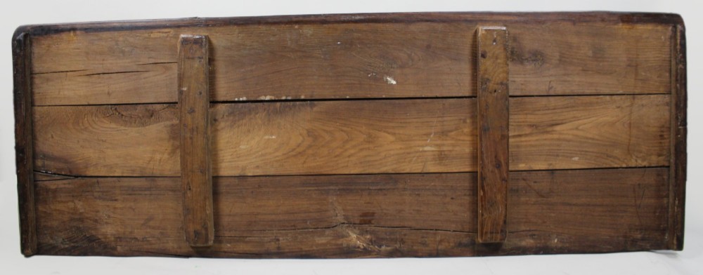 A low rectangular dark oak coffer with a plank lid and four carved recessed panels accented with brass studs. View X
