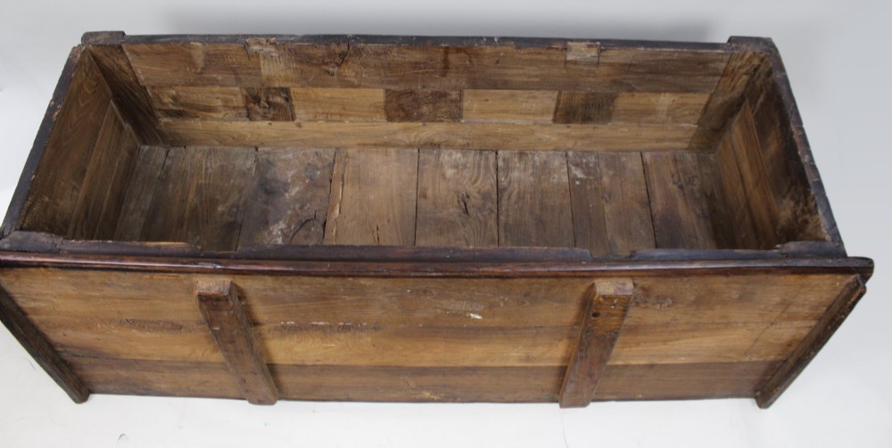 A low rectangular dark oak coffer with a plank lid and four carved recessed panels accented with brass studs. View XII