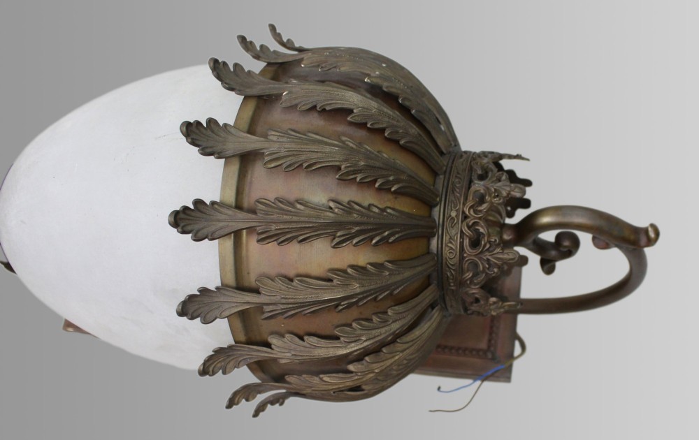 An antique brass wall lantern featuring a frosted ovoid glass shade draped with cast acanthus leaves and topped with a decorative cresting collar. View VI