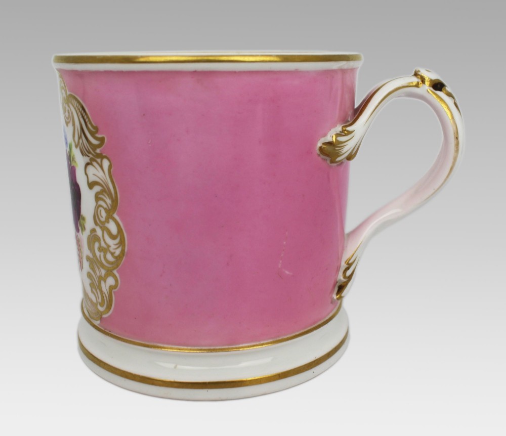 A mid-19th century cylindrical porcelain tankard featuring a Rose Pompadour pink ground, a gilded rococo scroll cartouche with hand-painted flowers, and a gilded handle. View VIII