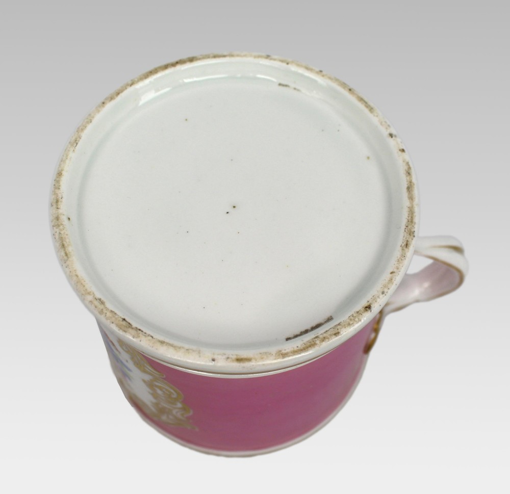 A mid-19th century cylindrical porcelain tankard featuring a Rose Pompadour pink ground, a gilded rococo scroll cartouche with hand-painted flowers, and a gilded handle. View IX