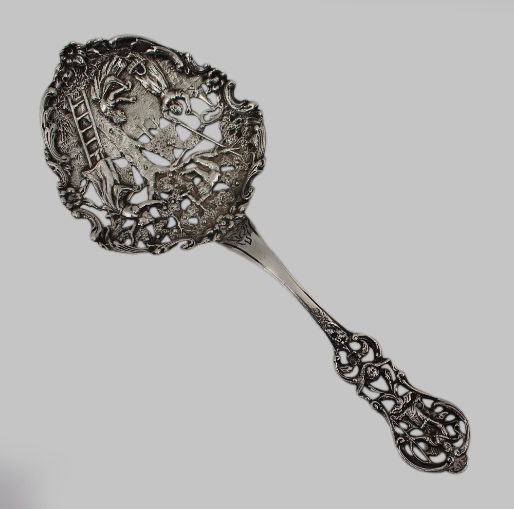 An antique Flemish silver spoon featuring an intricately pierced bowl decorated with a figurative orchard scene and a scrolling openwork handle. View III
