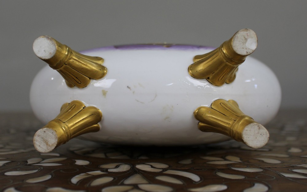 A white porcelain moon flask vase with twin gilded handles, four scroll feet, and a hand-painted portrait of a woman in a purple hat signed Baston. View VII
