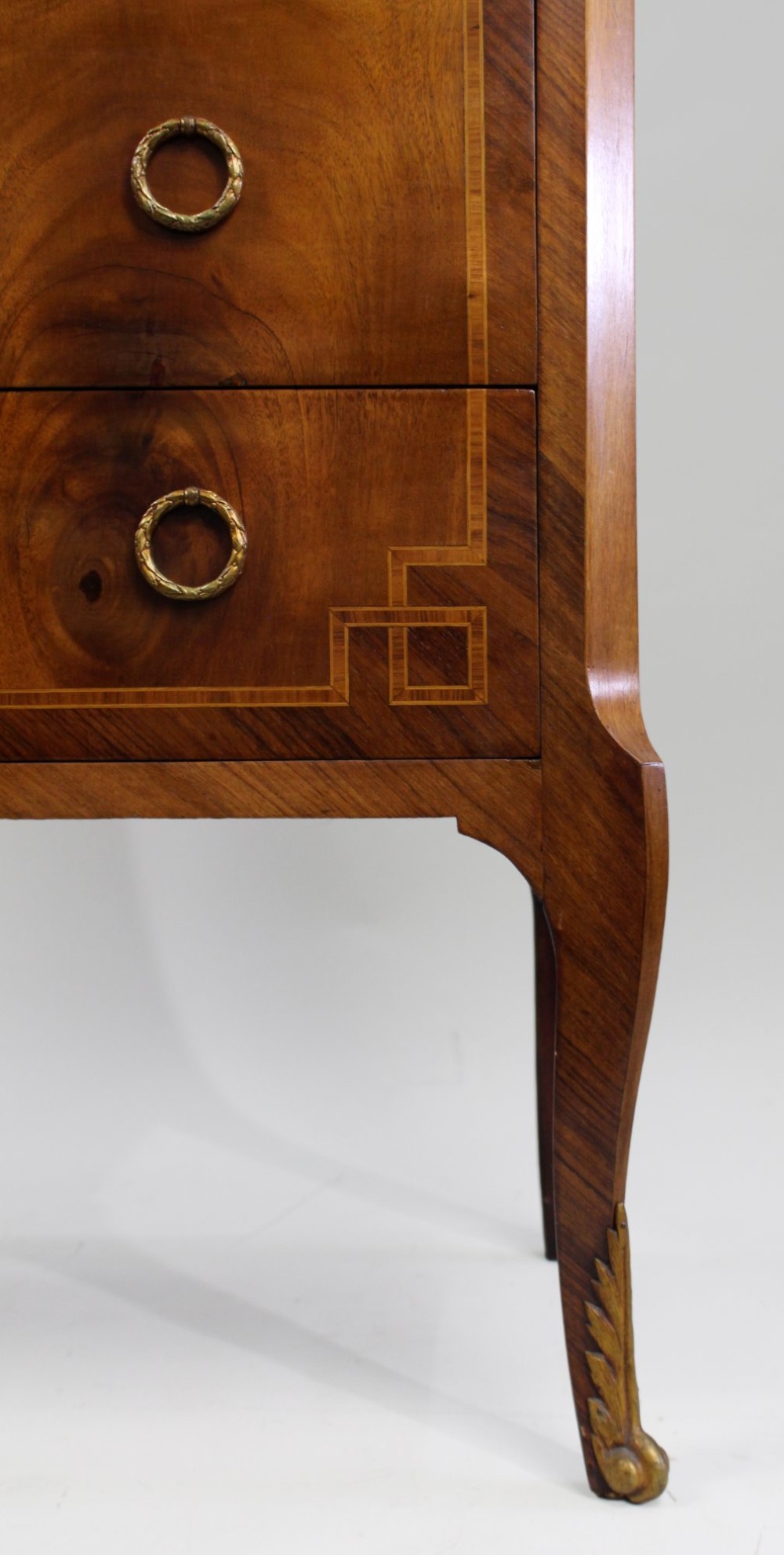 A French Louis XVI style timber commode featuring three drawers with geometric inlaid veneer, gilt-bronze ring handles, and a red variegated marble top. View IX