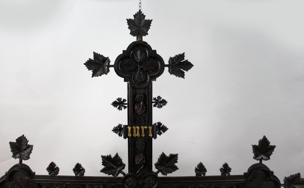 A 19th-century dark carved wood cross adorned with detailed foliate motifs and a gilt INRI inscription at the upper section. View II