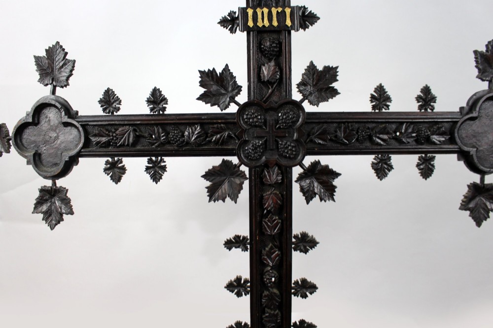 A 19th-century dark carved wood cross adorned with detailed foliate motifs and a gilt INRI inscription at the upper section. View IV