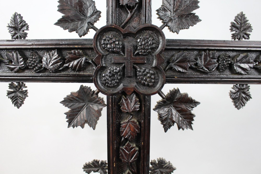 A 19th-century dark carved wood cross adorned with detailed foliate motifs and a gilt INRI inscription at the upper section. View VII