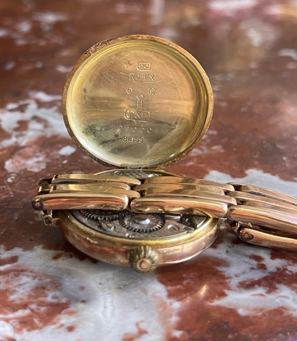 An antique circular 9ct gold wristwatch with a cream enamel dial, Arabic numerals, red twelve, and an expanding gold link bracelet. View II