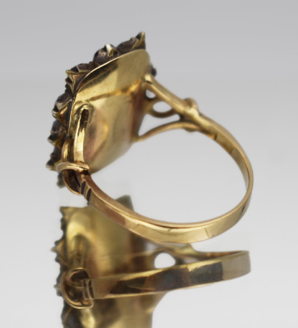 A Victorian yellow gold mourning ring featuring a central rectangular hair compartment surrounded by a halo of faceted purple glass stones. View III