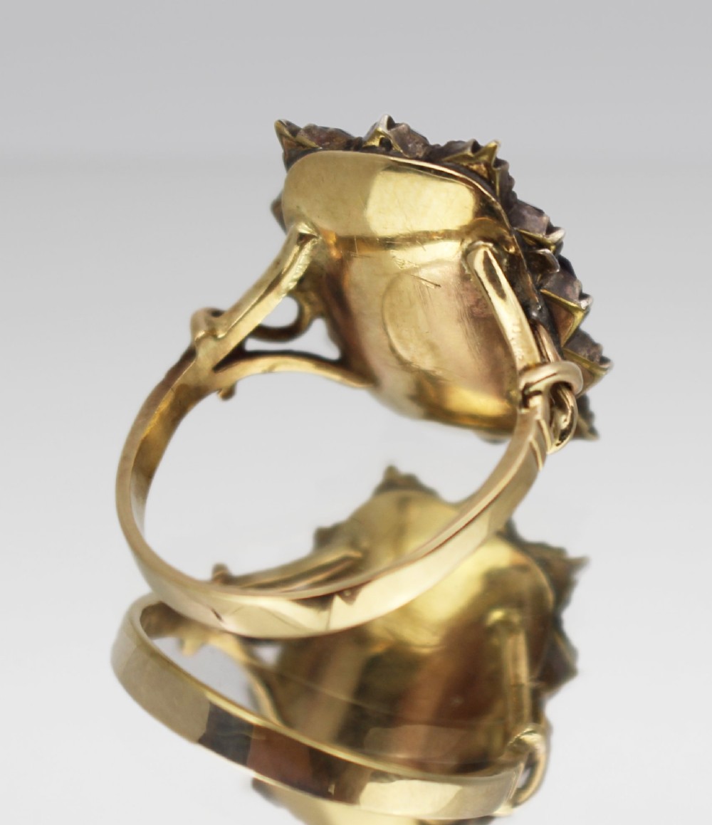A Victorian yellow gold mourning ring featuring a central rectangular hair compartment surrounded by a halo of faceted purple glass stones. View IV