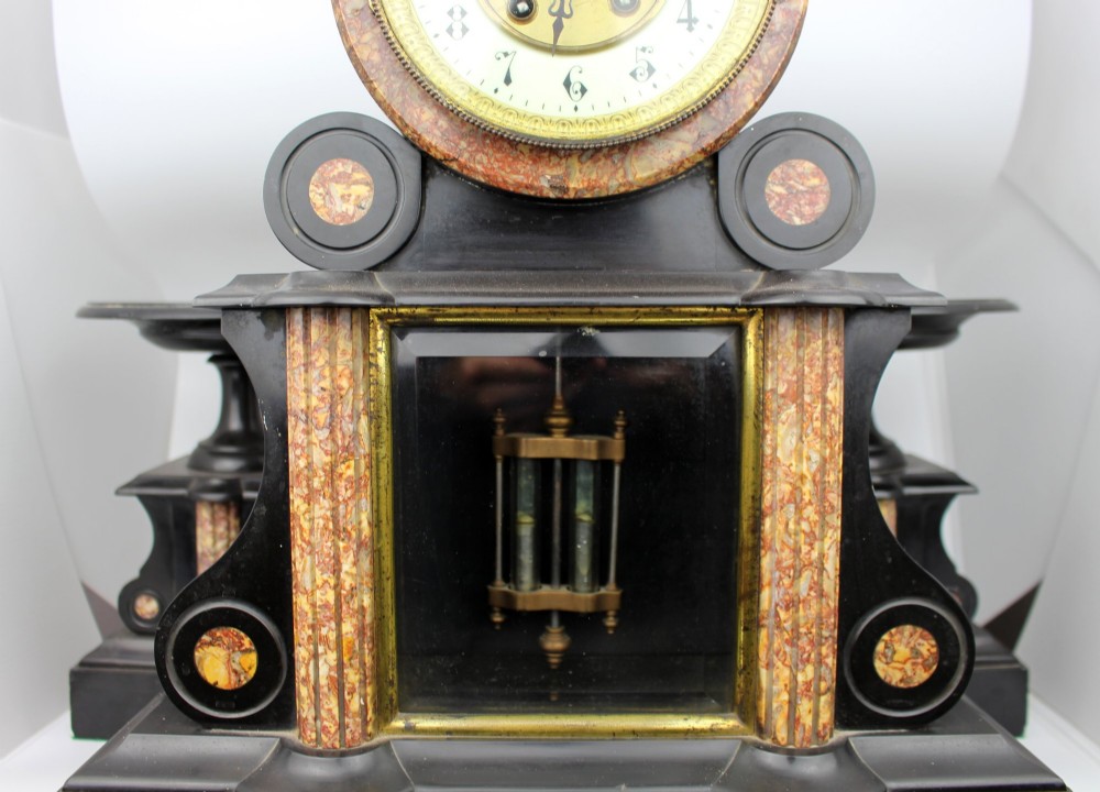 A 19th-century French black slate and red variegated marble clock garniture set with a central architectural clock and flanking side tazzas. View III