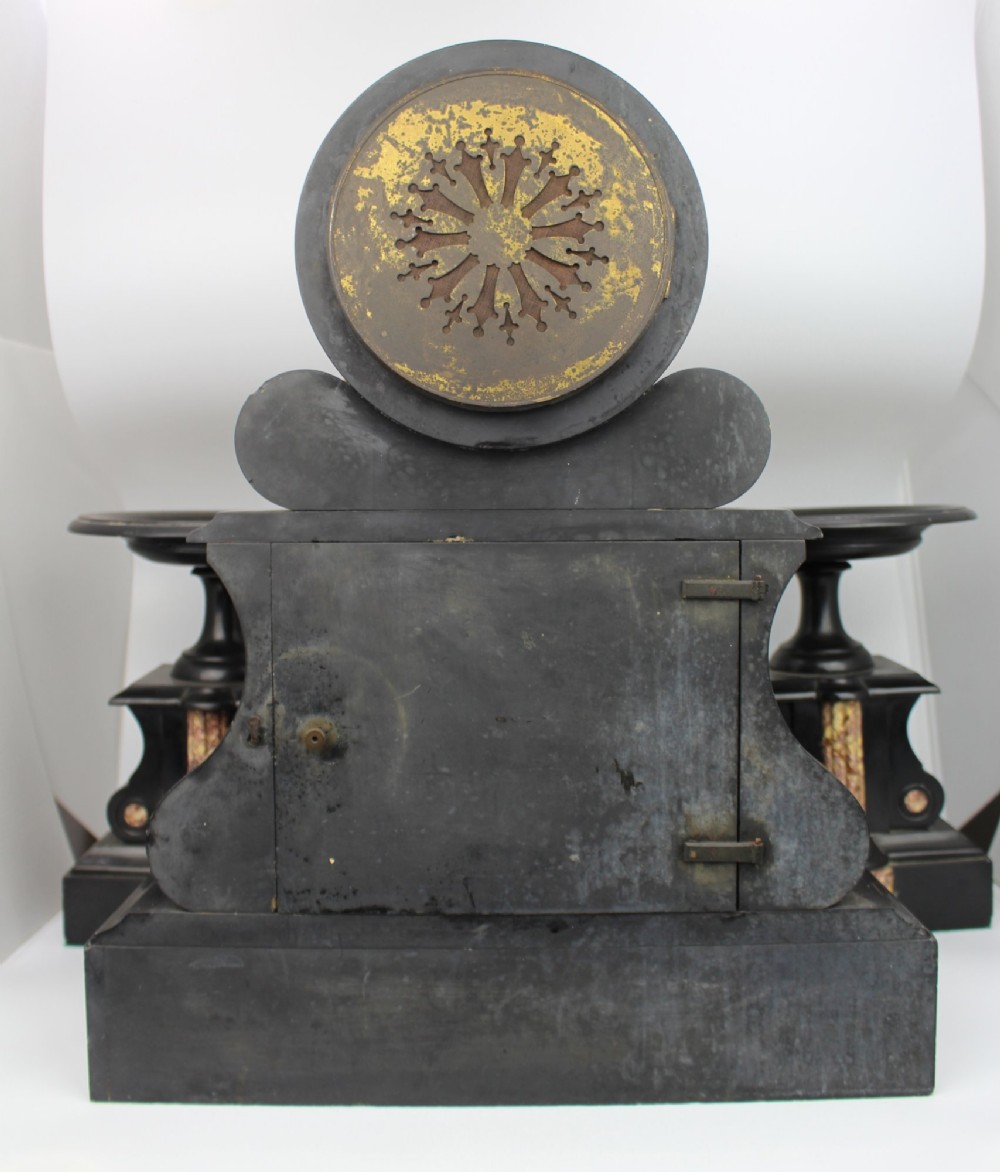 A 19th-century French black slate and red variegated marble clock garniture set with a central architectural clock and flanking side tazzas. View VI