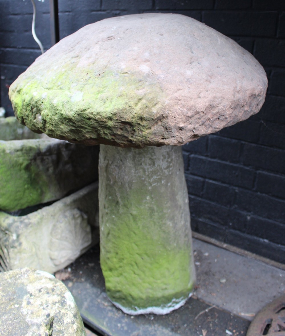 A two-piece antique sandstone staddle stone featuring a rounded mushroom cap resting on a tapered cylindrical pedestal base with moss coverage.