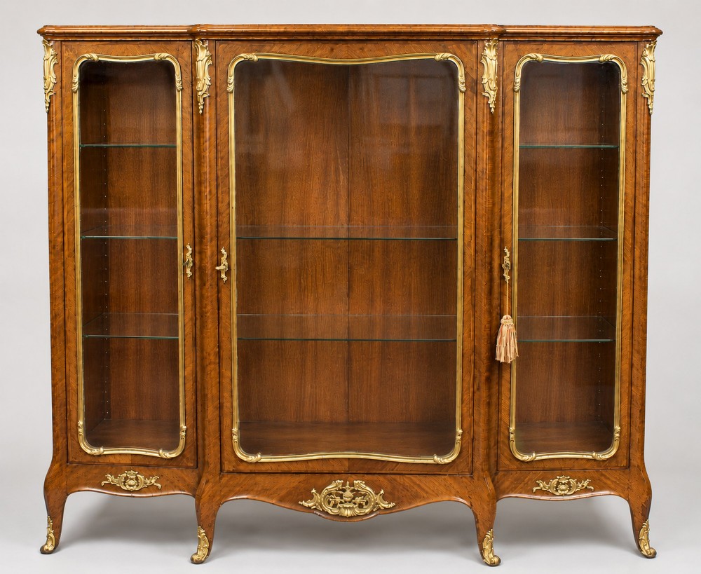 A large French kingwood display cabinet featuring three glass doors, gilded bronze mounts, and cabriole legs.