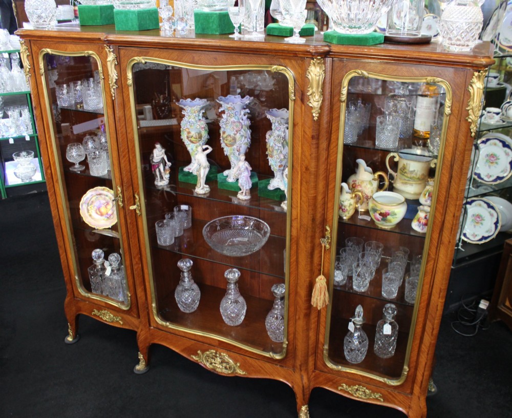 A large French kingwood display cabinet featuring three glass doors, gilded bronze mounts, and cabriole legs. View V