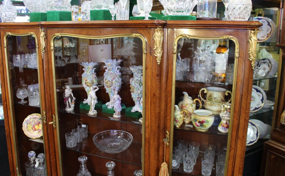 A large French kingwood display cabinet featuring three glass doors, gilded bronze mounts, and cabriole legs. View VI