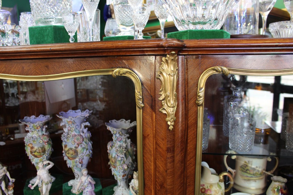 A large French kingwood display cabinet featuring three glass doors, gilded bronze mounts, and cabriole legs. View VII