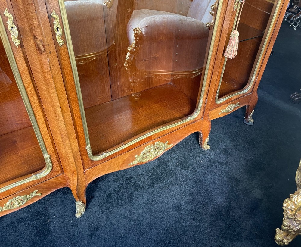 A large French kingwood display cabinet featuring three glass doors, gilded bronze mounts, and cabriole legs. View XI
