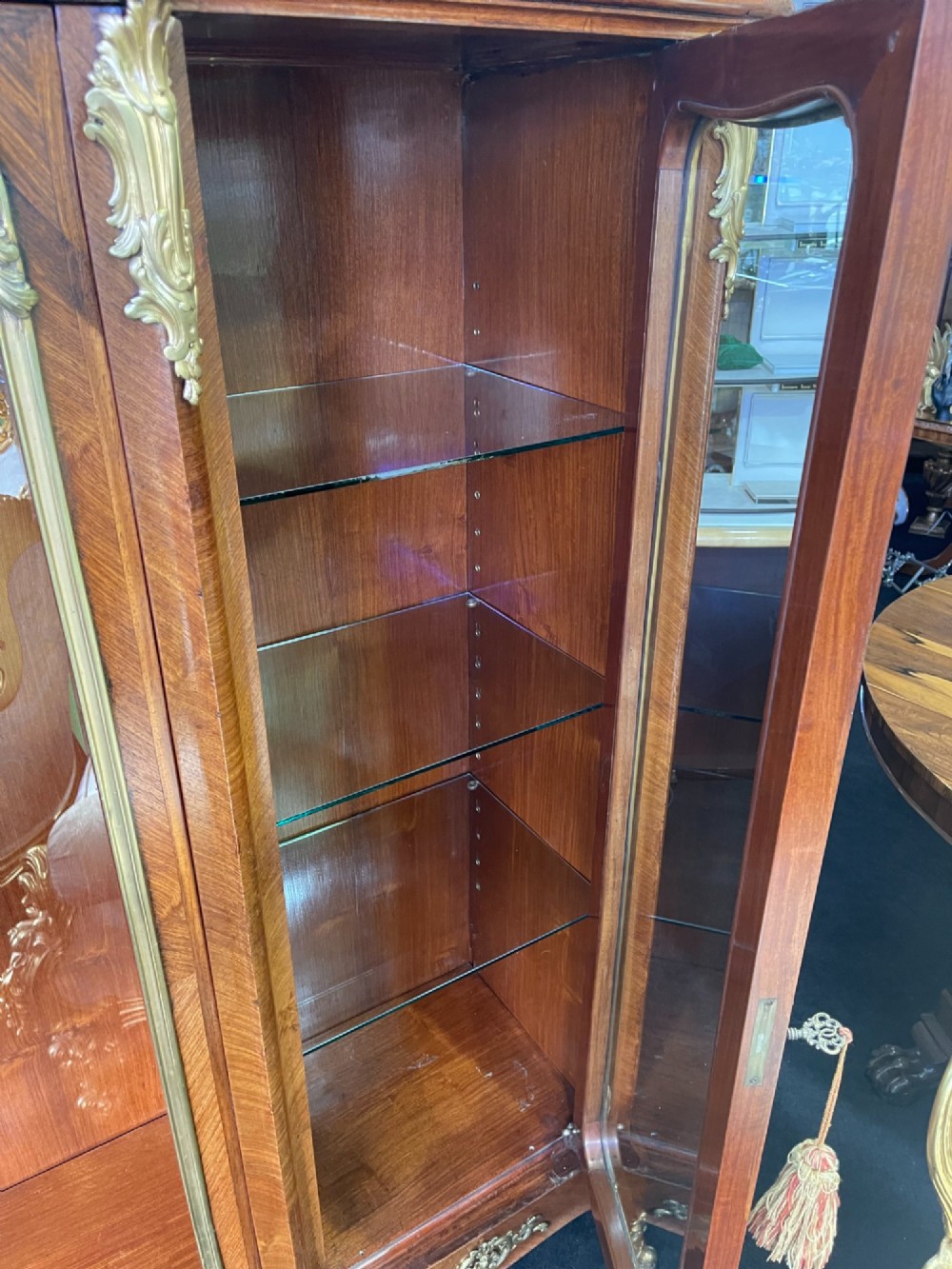 A large French kingwood display cabinet featuring three glass doors, gilded bronze mounts, and cabriole legs. View XII