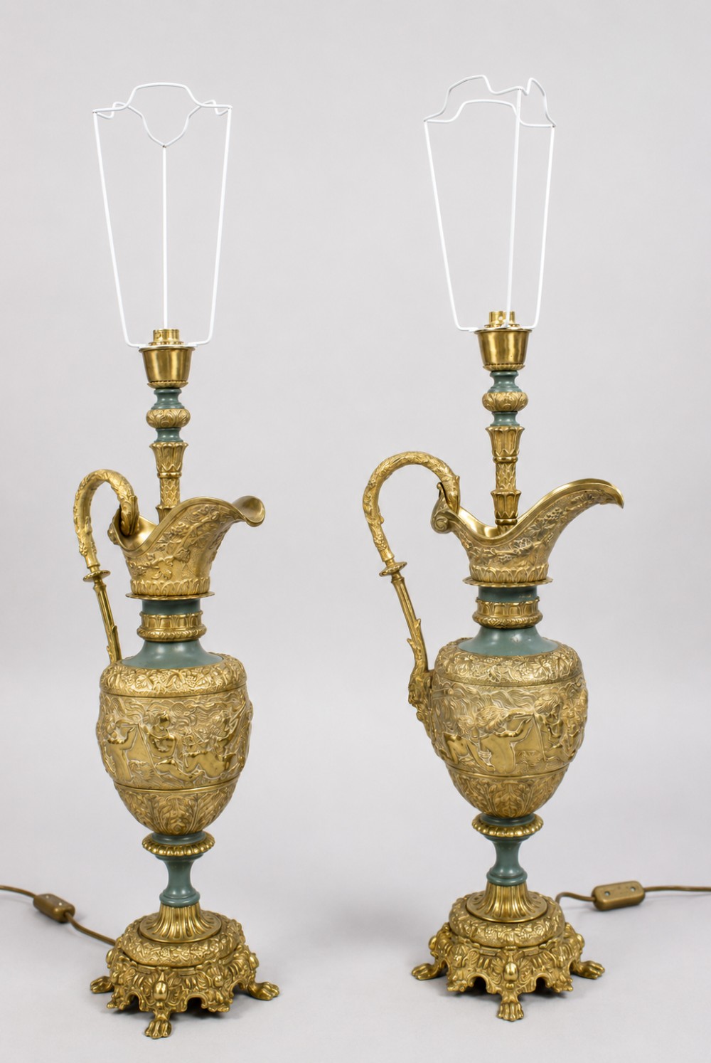 A pair of late nineteenth-century gilt metal table lamps fashioned in the shape of classical ewers with relief carving and green painted accents.