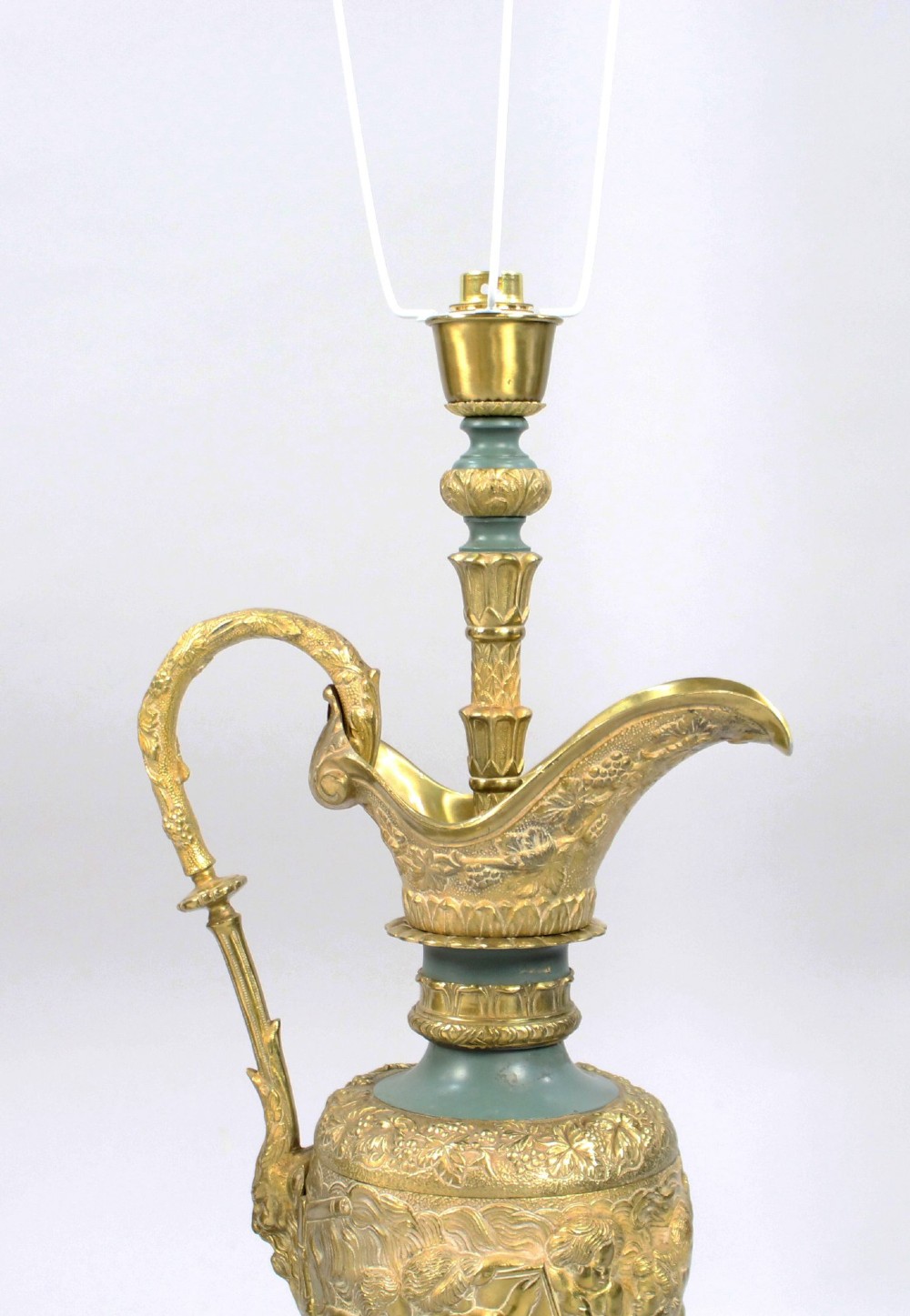 A pair of late nineteenth-century gilt metal table lamps fashioned in the shape of classical ewers with relief carving and green painted accents. View V