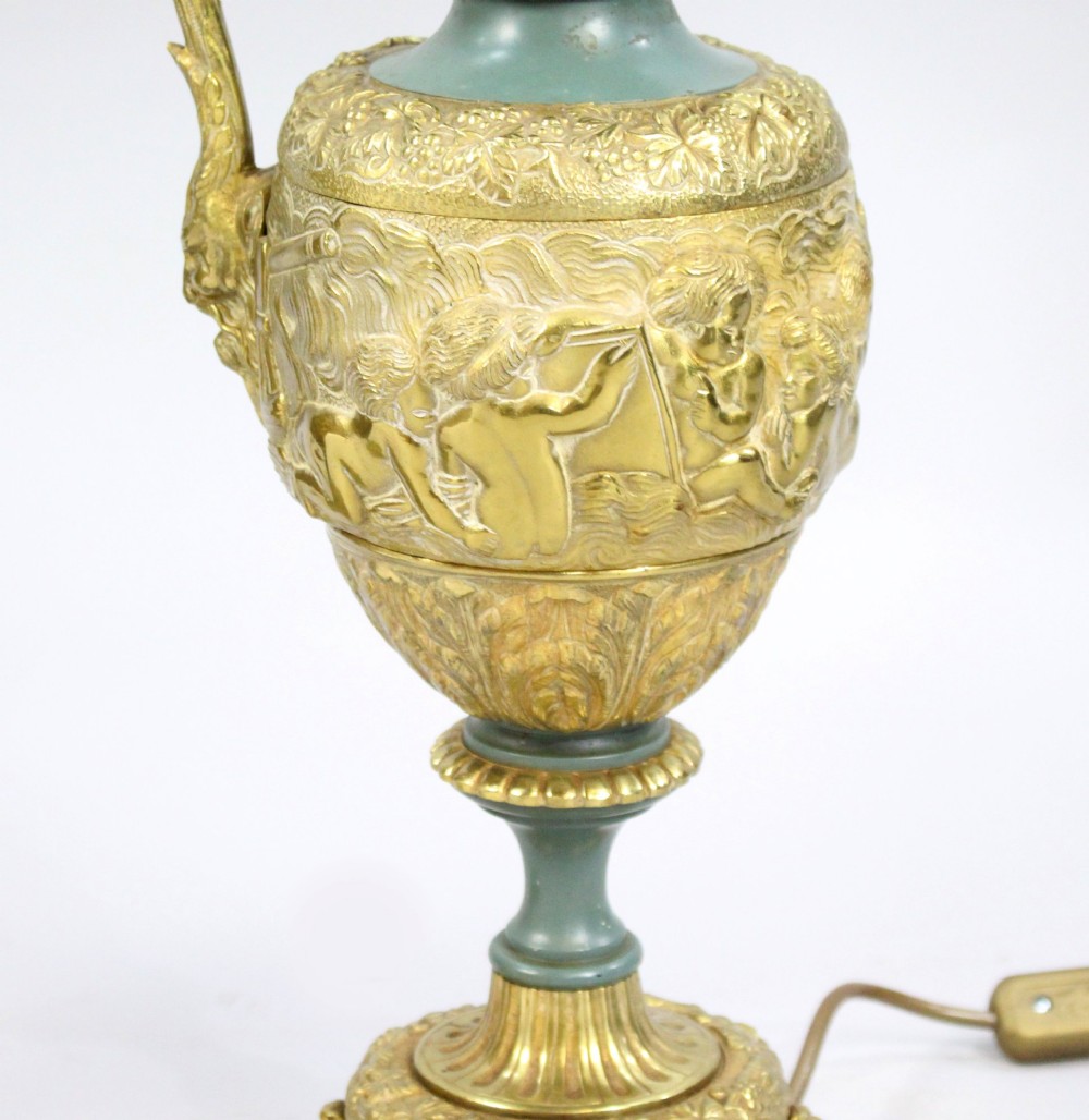 A pair of late nineteenth-century gilt metal table lamps fashioned in the shape of classical ewers with relief carving and green painted accents. View VII