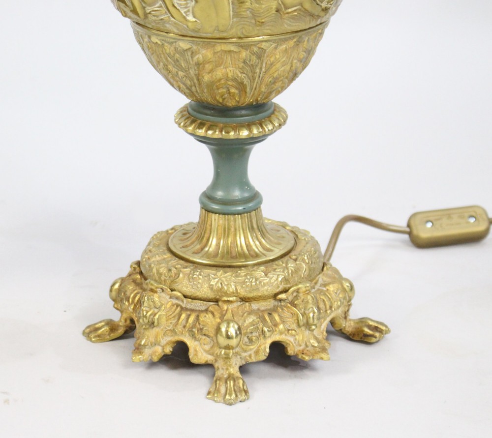 A pair of late nineteenth-century gilt metal table lamps fashioned in the shape of classical ewers with relief carving and green painted accents. View IX