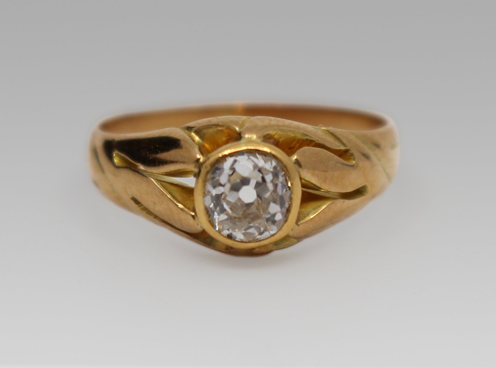 An antique rose gold ring featuring a central round old-cut diamond set within carved shoulders.