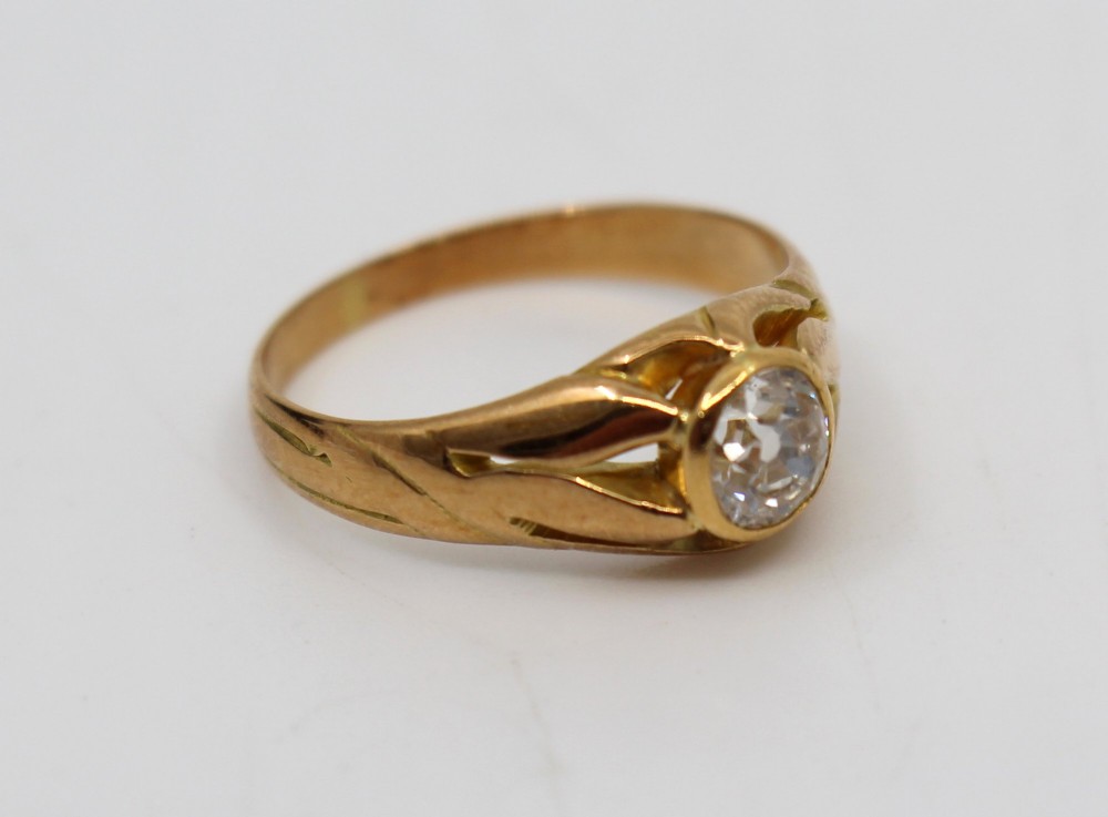 An antique rose gold ring featuring a central round old-cut diamond set within carved shoulders. View II