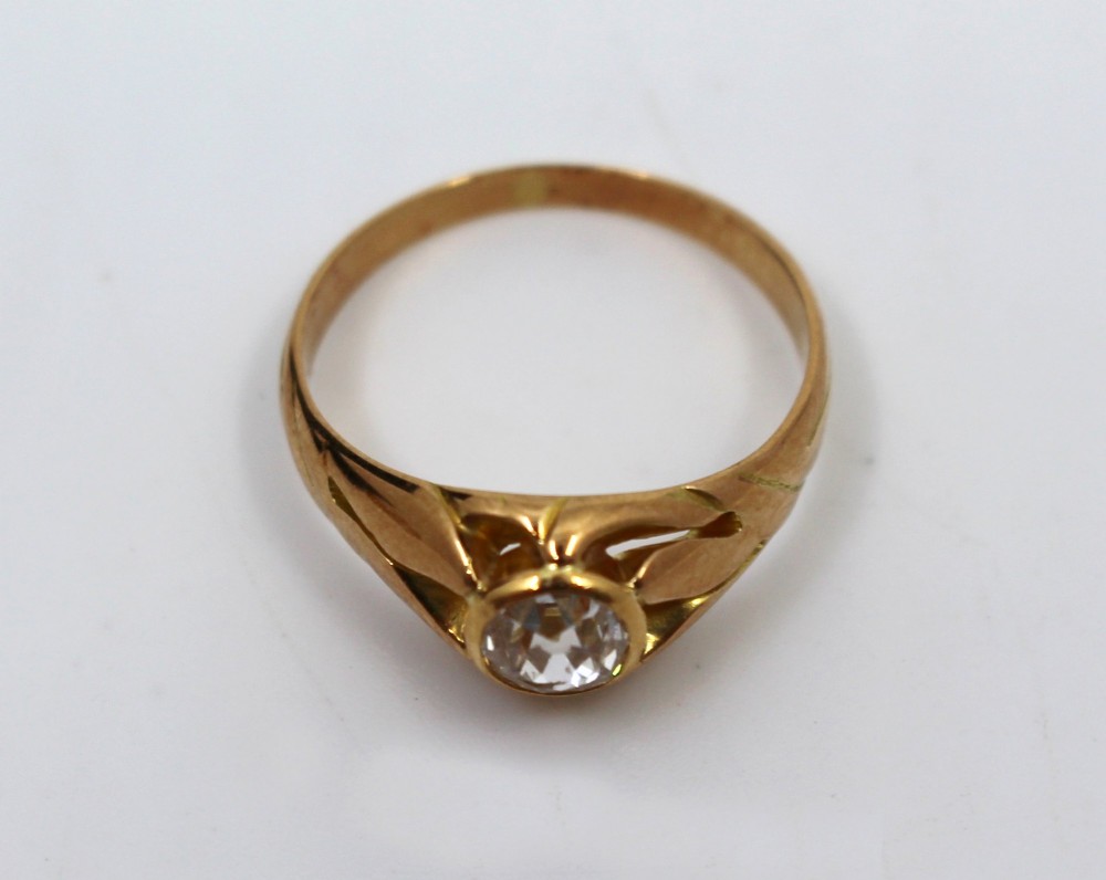 An antique rose gold ring featuring a central round old-cut diamond set within carved shoulders. View III
