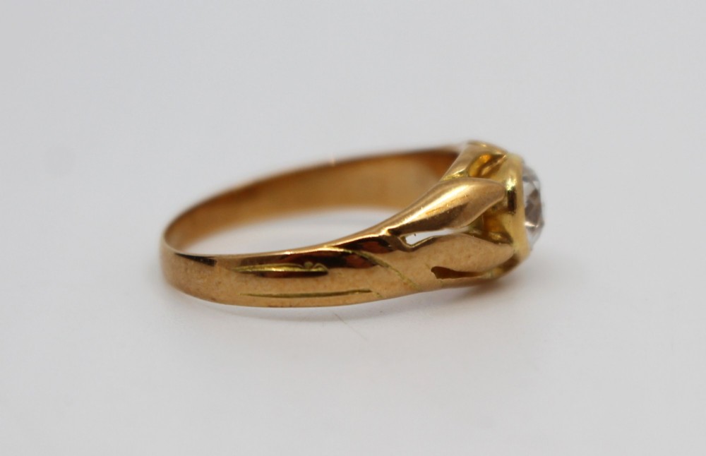 An antique rose gold ring featuring a central round old-cut diamond set within carved shoulders. View V