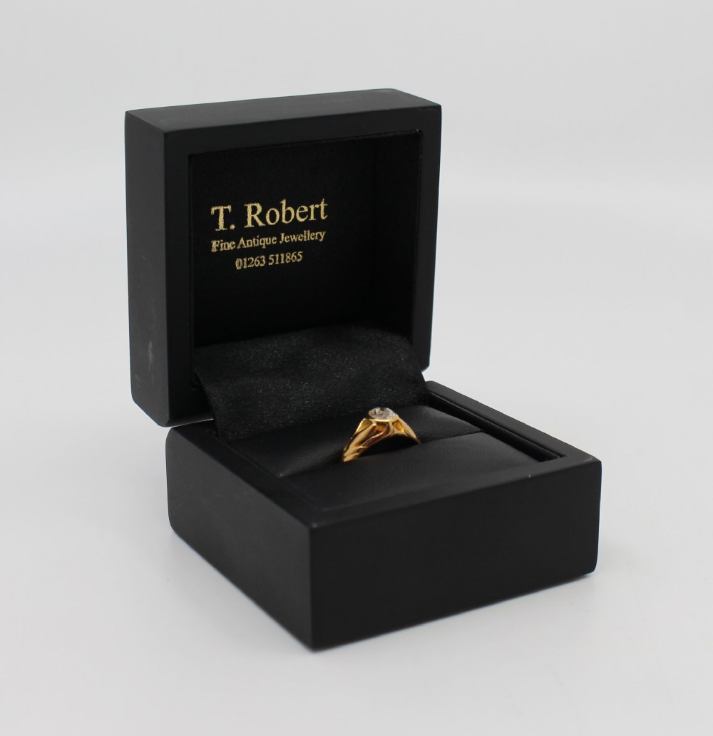 An antique rose gold ring featuring a central round old-cut diamond set within carved shoulders. View VI