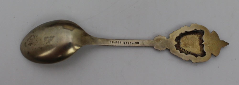 A cased set of six sterling silver demitasse spoons featuring colourful enamelled crest finials set inside a textured brown presentation box. View IV