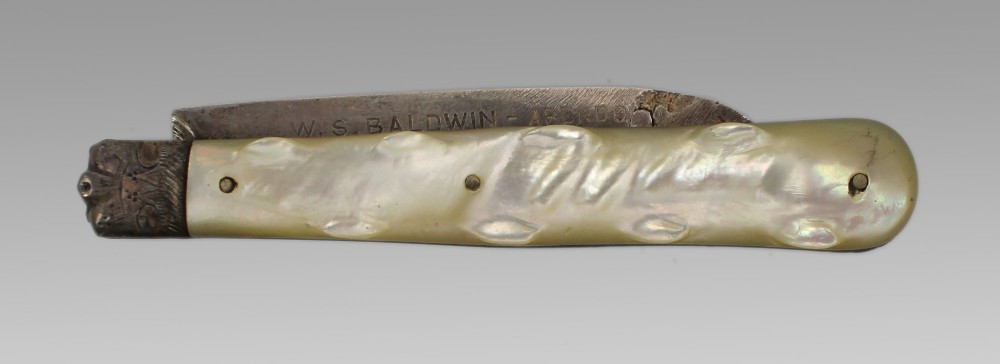 An antique folding fruit knife featuring carved mother of pearl handle scales, an engraved silver bolster, and a steel blade.