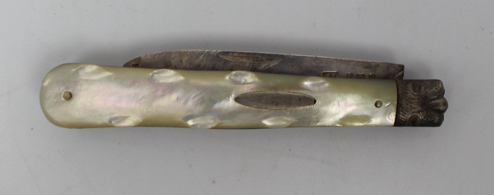 An antique folding fruit knife featuring carved mother of pearl handle scales, an engraved silver bolster, and a steel blade. View II