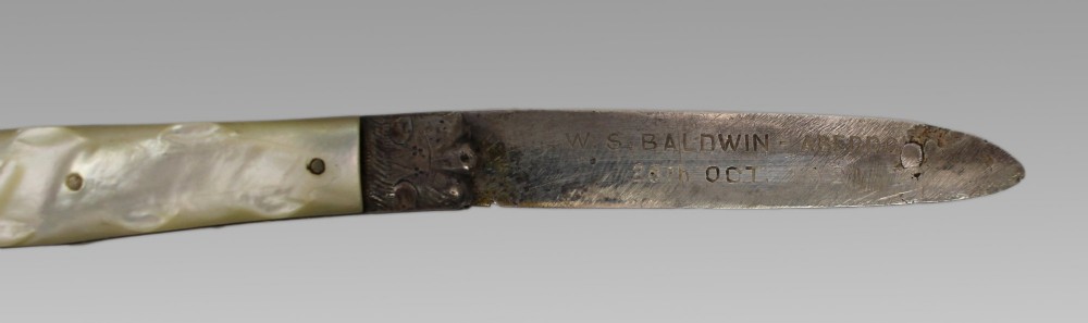 An antique folding fruit knife featuring carved mother of pearl handle scales, an engraved silver bolster, and a steel blade. View III