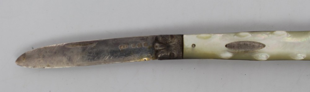 An antique folding fruit knife featuring carved mother of pearl handle scales, an engraved silver bolster, and a steel blade. View IV