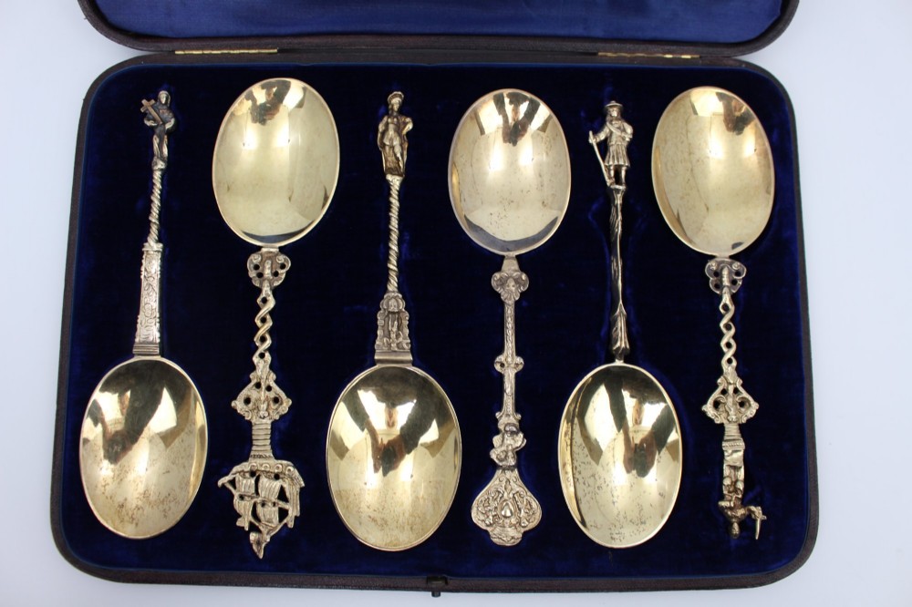 A set of six silver-gilt apostle spoons with cast figural finials and decorative shanks presented inside a dark blue velvet-lined fitted display case. View III