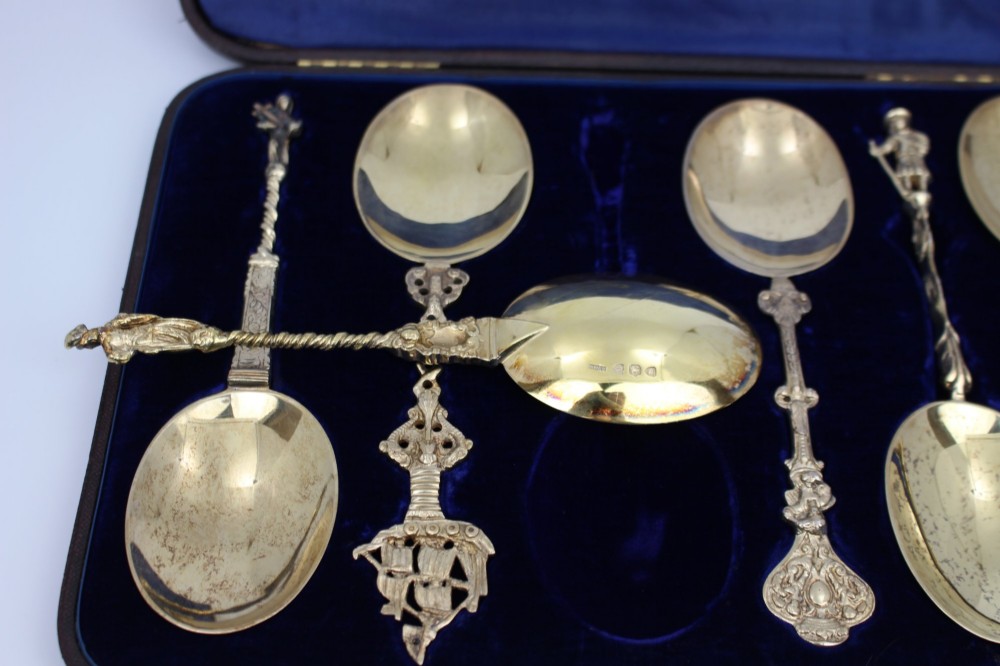 A set of six silver-gilt apostle spoons with cast figural finials and decorative shanks presented inside a dark blue velvet-lined fitted display case. View IV
