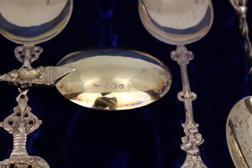 A set of six silver-gilt apostle spoons with cast figural finials and decorative shanks presented inside a dark blue velvet-lined fitted display case. View V