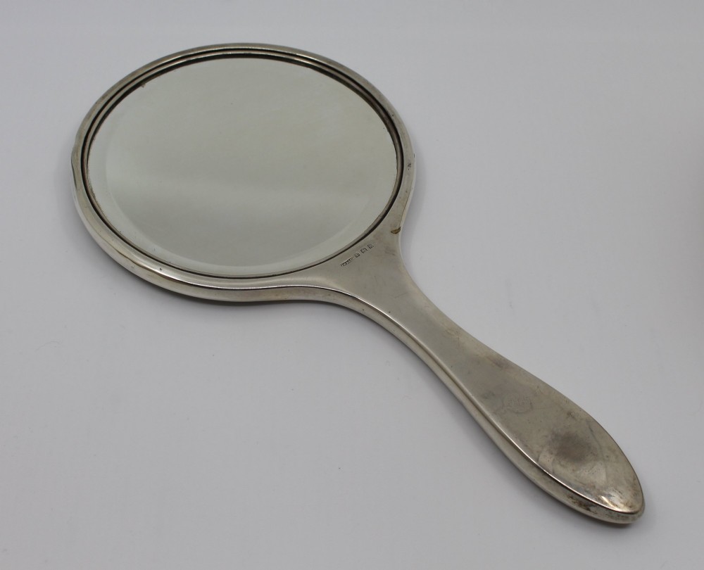 A five-piece Art Deco sterling silver and faux tortoiseshell vanity set featuring a hand mirror, two handled hairbrushes, and two clothes brushes with silver leaf-wreath inlays. View IX